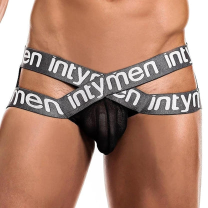 A close-up highlights a person wearing the Intymen Cross Jockstrap, with crisscrossed black straps over mesh fabric. This striking design stands out against the white background, emphasizing the garments versatility and style.