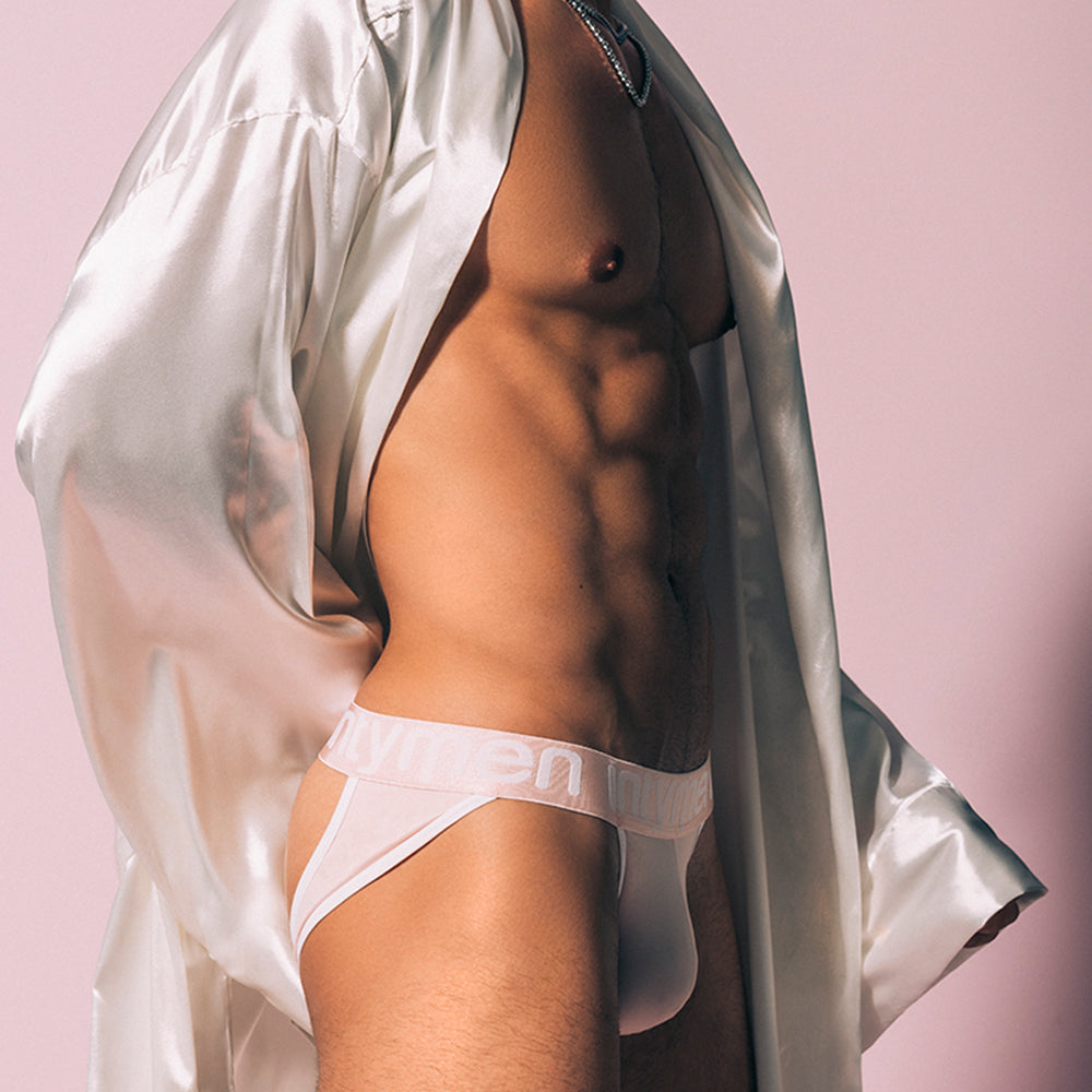 A person wearing the sleek Intymen Trevi Jockstrap stands against a pink background, highlighting the contoured pouch and showcasing their toned midsection and side profile.
