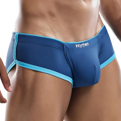 A person wears Intymen Tranquility Boxer Trunks with blue fabric and light blue trim, ensuring a comfortable fit and supportive pouch. The waistband prominently features the Intymen brand name. The image showcases the lower torso and upper thighs.
