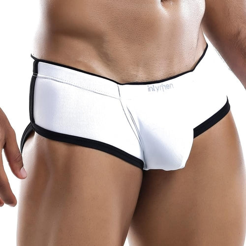 A person wears Intymen Tranquility Boxer Trunks with white fabric, black trim, and a supportive pouch. Cut-out sides and branded waistband highlight a comfortable fit. The sleek design focuses on the lower torso and legs against a plain background.