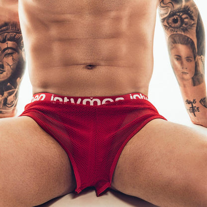An individual with tattooed arms is wearing the Intymen Jock Mesh Cover. The torso and upper legs are highlighted, showcasing the breathable texture and supportive design. A neutral backdrop accentuates both the tattoos and Intymen clothing.