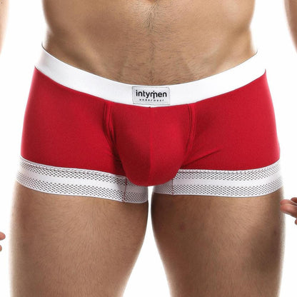 Someone wearing Intymen Quads Trunk, featuring red fabric with a white waistband and mesh accents at the leg openings. The centered brand label on the waistband stands out, and the lighting emphasizes the premium quality and tailored fit of this fashionable piece.
