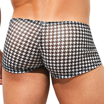 A person is seen from behind wearing Intymen Gales Trunk swimwear, showcasing a black and white houndstooth pattern. The stretchy fabric ensures a fitted look, while the simple light-colored background highlights the sleek design of these Intymen trunks.