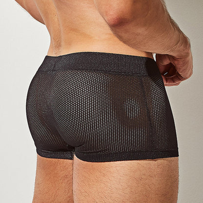 The image showcases a person from the back wearing Intymens black Bulge Pouch Athletic Boxer, highlighting its breathable mesh texture and fit. The focus is on their glowing skin at the lower back and waist area.