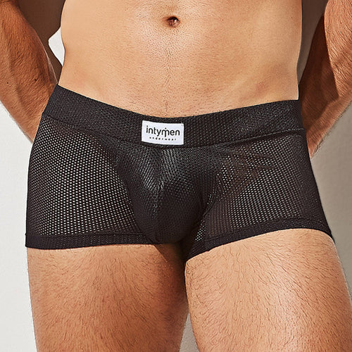 A close-up reveals someone in Intymen Bulge Pouch Athletic Boxer briefs, featuring a black mesh design with a white Intymen waistband. The breathable, see-through mesh showcases a textured look and C-Shape Pouch, as their hands rest at their sides.