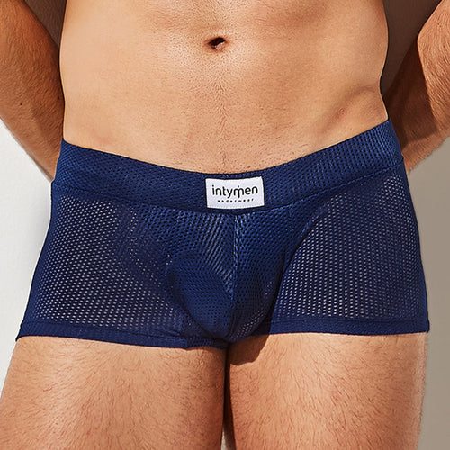 A person is wearing Intymen Bulge Pouch Athletic Boxer in navy blue with breathable mesh and a C-Shape Pouch, featuring a waistband label that reads intymen, focusing on the lower torso and upper thighs against a neutral background.
