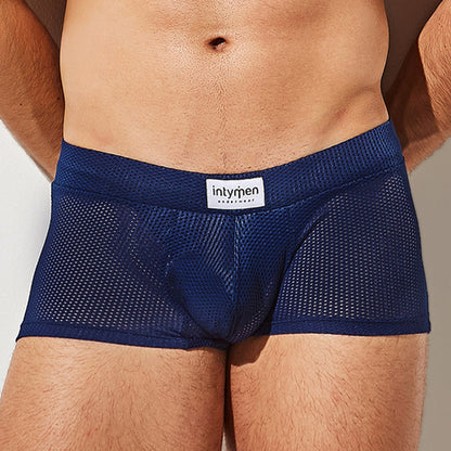 A person is wearing Intymen Bulge Pouch Athletic Boxer in navy blue with breathable mesh and a C-Shape Pouch, featuring a waistband label that reads intymen, focusing on the lower torso and upper thighs against a neutral background.