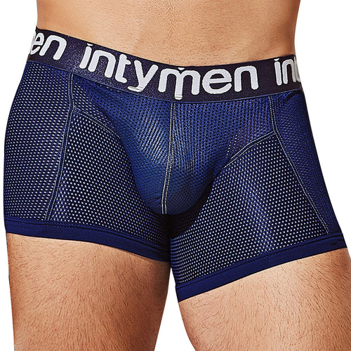 A person sports Intymen ING081 Luxury Trunk Boxers, made of premium fabric with a snug fit, featuring blue textured material and a black intymen waistband. The design includes light stitching and a contouring pouch for comfort.