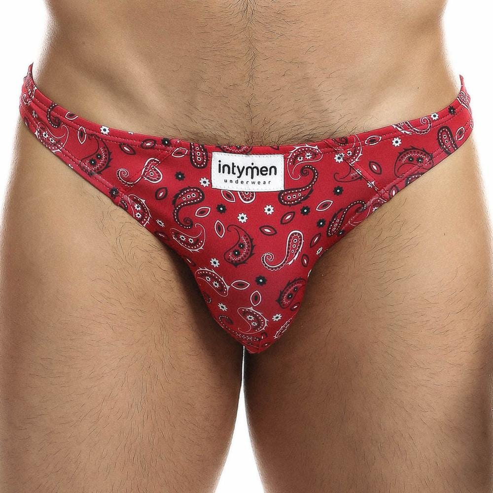 A person stands facing forward, wearing Intymen Sexy Boy Paisley Bikini in red, visible from the waist up.
