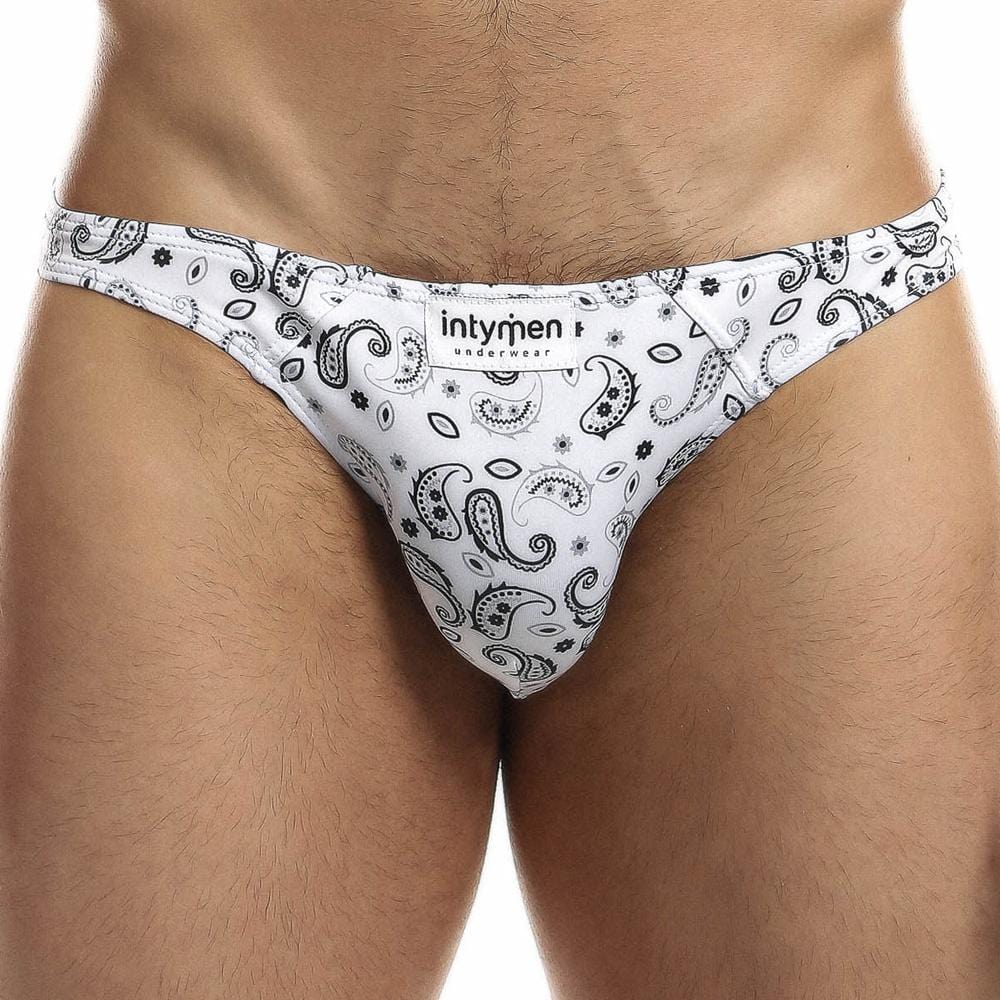 A close-up shows a person wearing Intymen Sexy Boy Paisley Bikini with an elegant Royal Paisley Print. The fabric blends black and gray paisley with floral designs, showcasing a refined style.