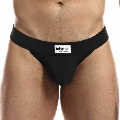 A person models the black Intymen Obscene Bikini, featuring the intymen brand label on the waistband. The front view highlights its comfortable fit, while its high-cut design adds a modern twist to this classic style.