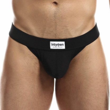 A person models the black Intymen Obscene Bikini, featuring the intymen brand label on the waistband. The front view highlights its comfortable fit, while its high-cut design adds a modern twist to this classic style.