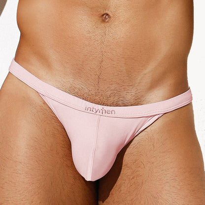 Someone is wearing light pink Intymen Roma Bikini underwear featuring the intymen logo on its waistband. The plain, light background highlights the style and comfort of this breathable mens bikini design.