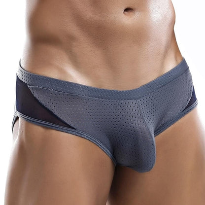 A person wearing Intymen Serenity Brief with a gray mesh and black side panels poses against a neutral backdrop. The breathable design ensures comfort and support, highlighted by a contour pouch, while the persons torso and upper thighs are visible.