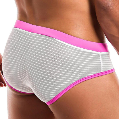 A person wearing Intymen Profile Briefs with pink and white stripes is seen from behind. They feature a bright pink waistband, leg bands, and a shaped support pouch against a plain white background.