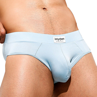 A person sports light blue underwear with the waistband branding Intymen Femme Brief from Intymen. The plain backdrop accentuates its design, showcasing both style and comfort.