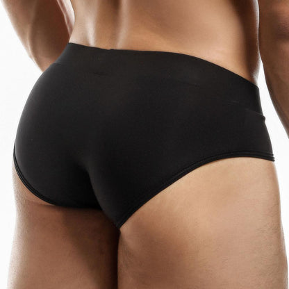 A person models the Intymen Femme Brief swim trunks from the back. This chic swimwear snugly accentuates their lower body against a plain backdrop, exuding both comfort and confidence.