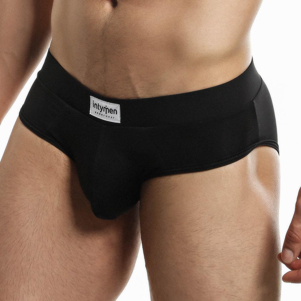 Wearing Intymen Femme Briefs, this person highlights the blend of style and comfort, with a visible Intymen label on the waistband. The plain background keeps the focus on the sleek underwear design.