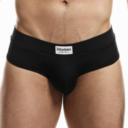 Someone in Intymen Femme Briefs, featuring a visible branded logo on the waistband, stands against a plain background, embodying effortless style and comfort.