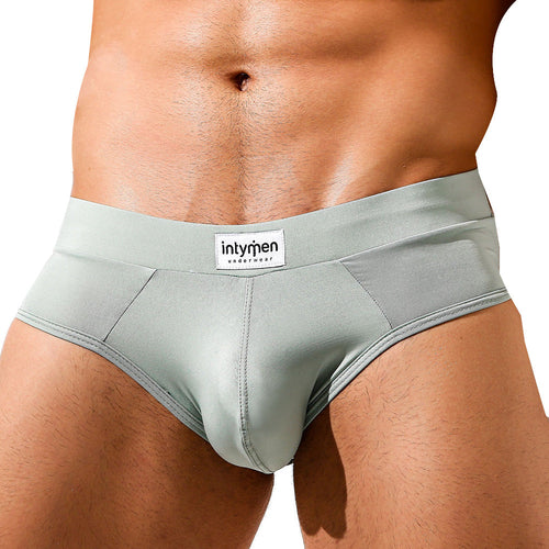 A close-up of a persons lower torso displays the Intymen Femme Brief in light gray, featuring the visible Intymen brand label on the waistband. The tan skin tone enhances the style and comfort, emphasizing the sleek design of this underwear.