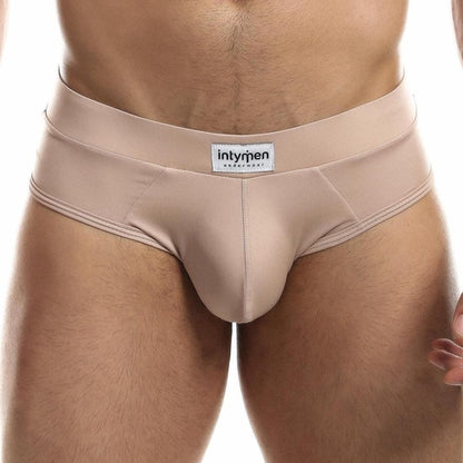 A person wears beige Intymen Femme Brief, highlighting its comfort and style while showcasing the fit and design on the torso and upper legs.