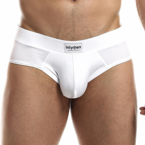 A person wearing sleek white Intymen Femme Briefs stands against a plain backdrop, showcasing the stylish waistband that displays Intymen, emphasizing comfort and fashion in this focused shot of the lower torso and underwear.