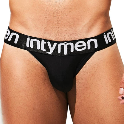 Close-up of a person wearing Intymen Peace Brief underwear, made from stretchable cotton with a thick black waistband. The word intymen is printed in white, delivering style and comfort against a plain background.