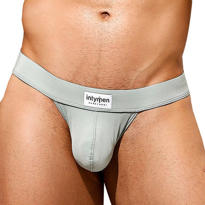 An individual is wearing an Intymen Sensual Thong in sleek, light gray with a visible brand label on the waistband. The image emphasizes the waist and hips, showcasing its comfortable fit.