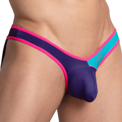 A person models in a vibrant bikini-style swimsuit with blue, pink, and turquoise tones resembling the Kyle Open Back Sporty Jockstrap by Kyle. The shiny fabric and minimal coverage highlight athletic support, focusing on the lower torso and upper legs.