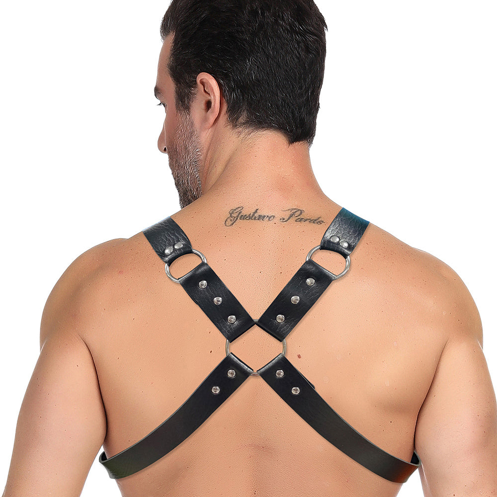 A man with a tattoo on his upper back wears the Miami Jock Harness from Miami Jock, crafted from black leather with metal rings and studs. The harness forms an X shape across his spine, enhancing the rugged aesthetic and accentuating his confident stance from behind.