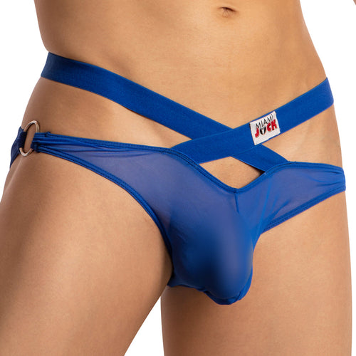 A person is wearing the Miami Jock Cross Strapped Sheer Brief, a blue mesh jockstrap with front crisscross straps, and a Miami Jock label. This sheer sensation brief includes metallic ring accents on the waistband.
