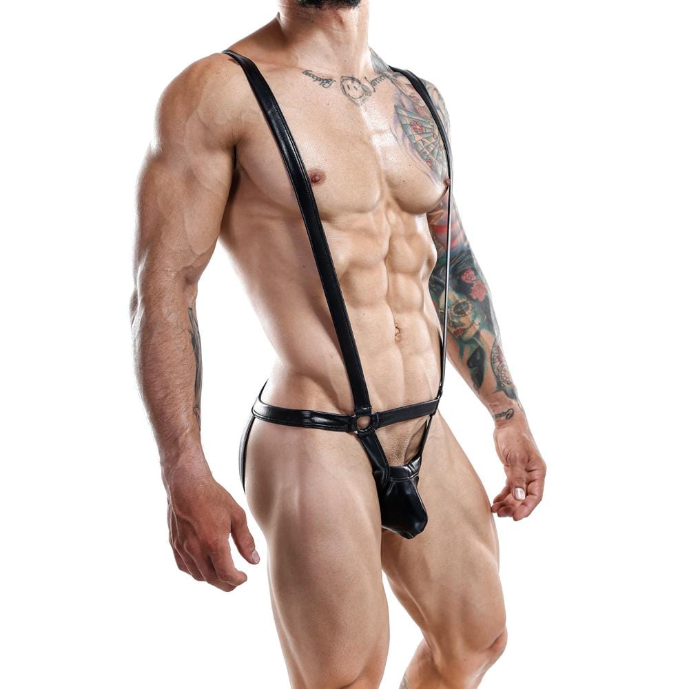 A muscular person wears a bold Miami Jock Bodysuit by Miami Jock, with the black leather harness highlighting their physique. Colorful tattoos cover their arms, and the plain white background showcases their attire and unique style.