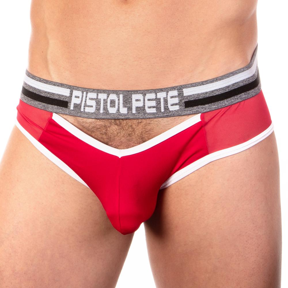 A person confidently models red Pistol Pete Dinger Jockstrap briefs, featuring white trim and a sleek black and silver waistband with the Pistol Pete label. The stylish design is highlighted against a pristine white backdrop, emphasizing its fashionable appeal.