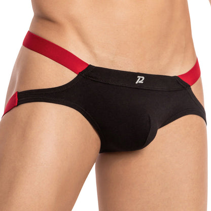 The close-up image shows someone wearing Pistol Pete Toro Jock underwear, featuring black fabric with red elastic straps. It highlights the bull-inspired design with a supportive pouch and a small logo at the front center, focusing on the midsection without revealing the persons face.