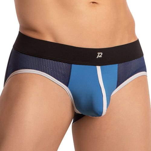 A person wearing the Pistol Pete Piping Bulge Pouch Jockstrap in blue and black with white trim. It has a black waistband with a small logo at the center, breathable fabric, and side net panels, reminiscent of classic Pistol Pete design.