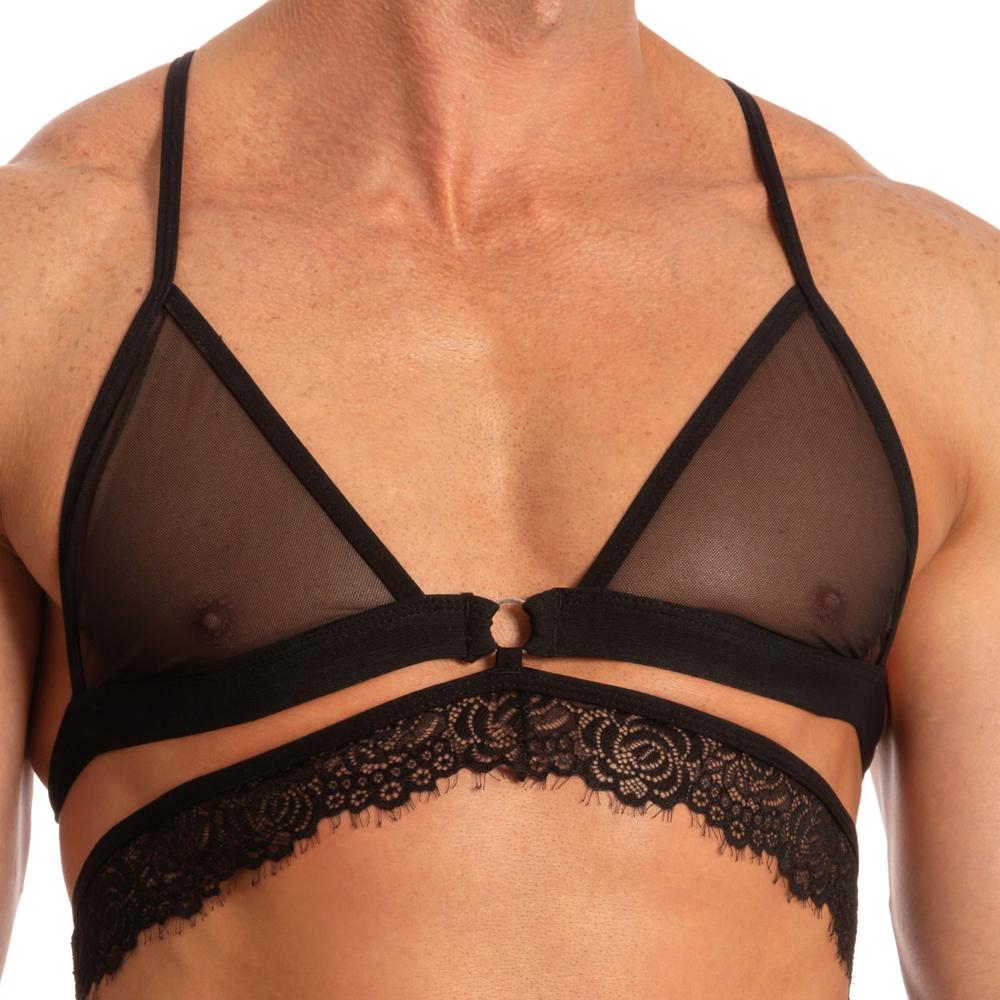 A muscular person wears Secret Males Secret Male SMA017 Justines Delight Bra in black, crafted from polyamide and spandex with thin straps, a central ring detail, and a delicate lace hem.
