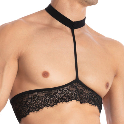 A person confidently wears the Secret Male Throbbin Top, a black halter neckline bralette with floral lace detailing and a collar strap, showcasing bold mens fashion against a white background.