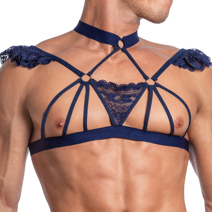 A person wears the Secret Male Seductive Floral Tops, a navy strappy harness with lace detailing at the shoulders and chest. The sheer fabric showcases circular metal connectors and a central triangular lace pattern against a plain white background.