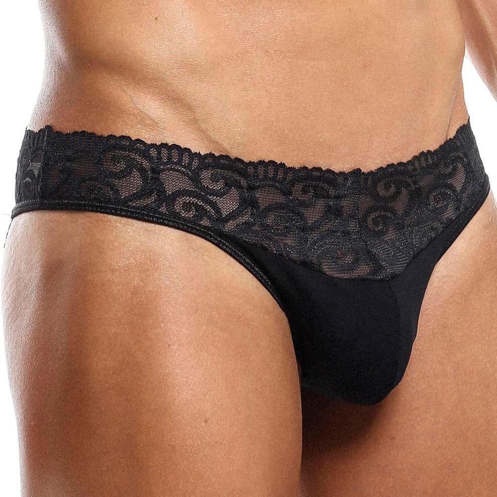 A model showcases the Secret Male SMI025 Lace Bottom Bikini by Secret Male, featuring intricate lace detailing around the waistband with solid fabric below. The image highlights the design focused on the midsection.