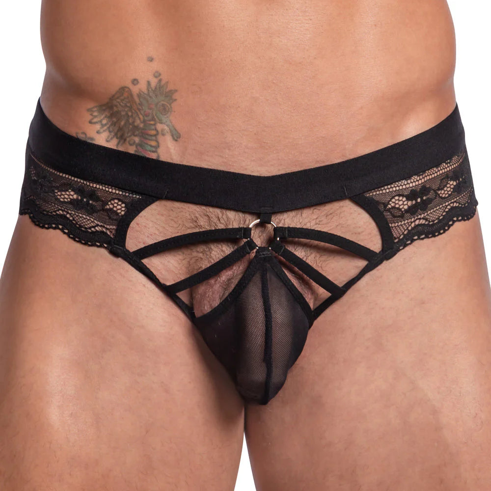 The image features a person wearing the Secret Male Steel Ring Sheer Bikini, showcasing black lace mens lingerie with floral detailing and a steel ring accent. A sheer fabric adds allure, along with an angel wing tattoo seen above the waistband on the persons side.