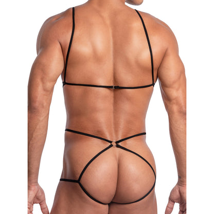 A person is seen from behind in the Secret Male SMV005 Designer See Through Body Suit, a minimalistic black piece made of polyamide. It features thin straps crossing the back and waist, forming a geometric pattern against a plain white background.