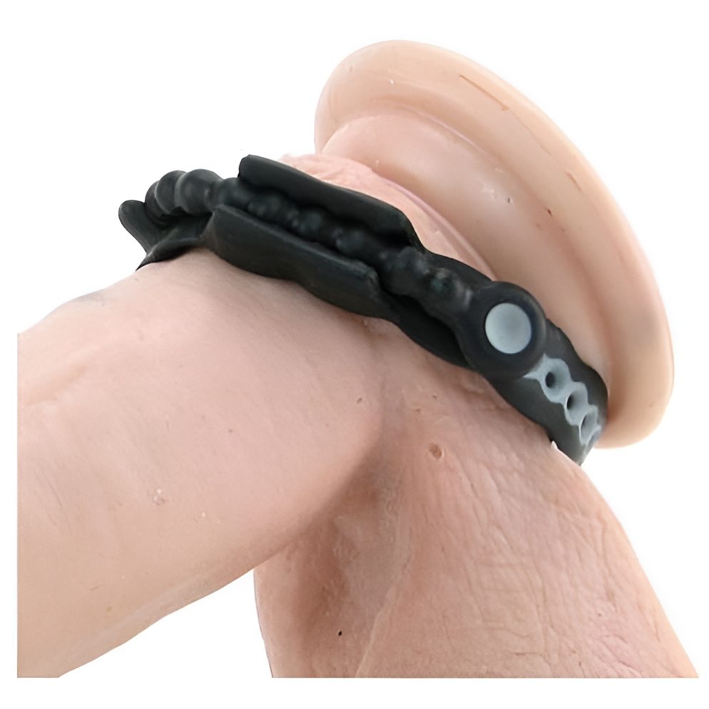 A close-up image shows the Speed Shift 17 Adjustments Cock Ring by Perfect Fit, wrapped around a beige cylindrical object. The black band, adorned with small decorative elements on a white background, highlights its texture, offering long-lasting pleasure with detailed design.