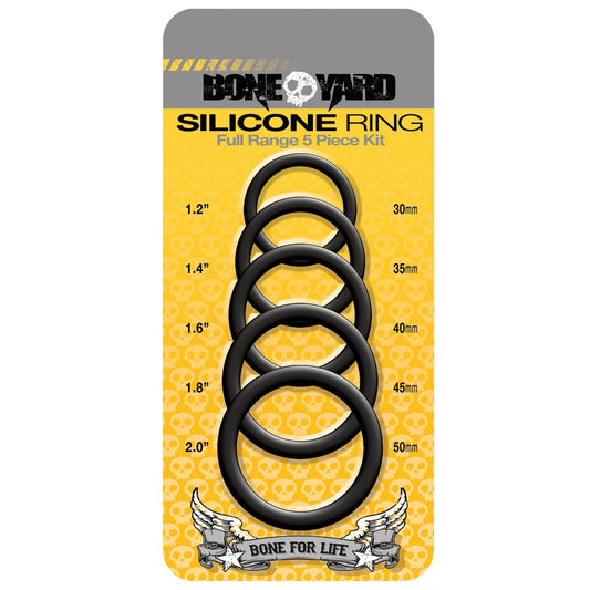 The Boneyard 5 pc Silicone Ring Kit by Boneyard features five pure silicone black cock rings (30mm, 35mm, 40mm, 45mm, and 50mm). The packaging has a vibrant yellow background with skull patterns for an edgy design.