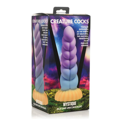 The Creature Cocks Unicorn Silicone Dildo, branded by Creature Cocks, features the Mystique design, resting in pastel packaging with a mystical forest and cosmic sky backdrop, highlighting its imaginative silicone craftsmanship.