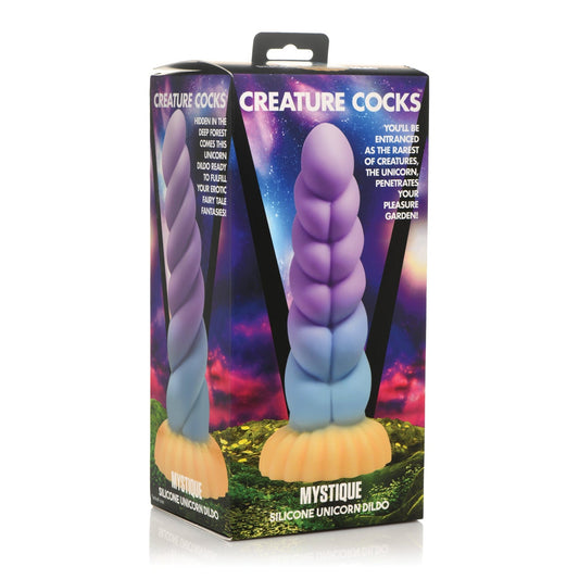 The Creature Cocks Unicorn Silicone Dildo, branded by Creature Cocks, features the Mystique design, resting in pastel packaging with a mystical forest and cosmic sky backdrop, highlighting its imaginative silicone craftsmanship.