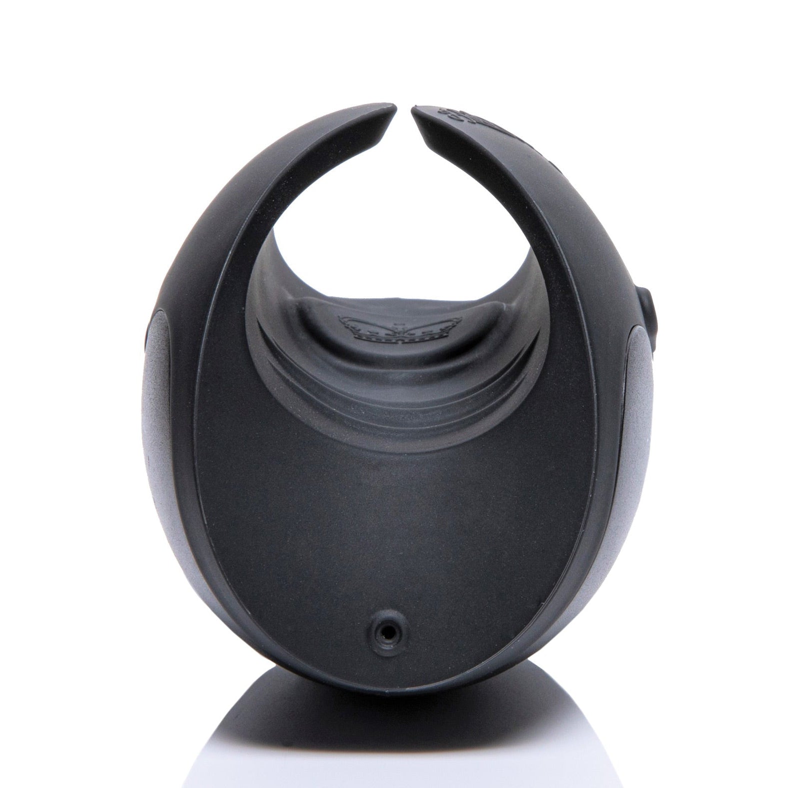 Close-up of a sleek, black circular wearable device with an open U-shape, smooth matte finish, and small logo on top. Displayed against a reflective white background, reminiscent of the Hot Octopuss Pulse Solo Essential by Hot Octopuss.