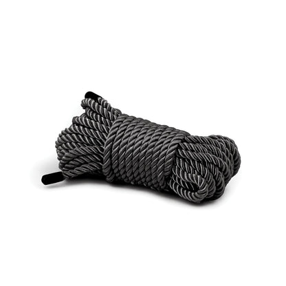 A neatly arranged coiled bundle of thick gray Bondage Couture Rope by Bondage Couture, made from high-quality synthetic material, is displayed on a white background, with black ends visible on each side.