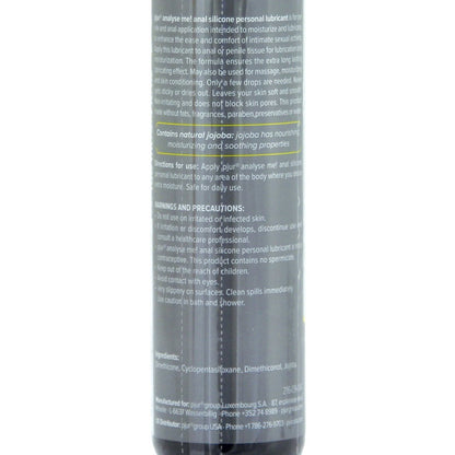 A close-up of the Pjur Analyze Me! Relaxing Anal Glide Silicone bottle highlights text about its natural jojoba for nourishing, moisturizing, and soothing. The lower part lists ingredients and cautionary details for this silicone-based lube.