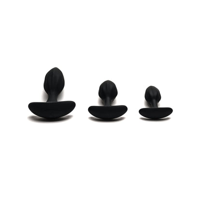 Three black plug-shaped objects, part of the Sport Fucker MotoVibe Plug N Play Kit, are lined up on a white background. Each has a rounded top and flat base, designed to enhance your booty workout with precision and comfort.