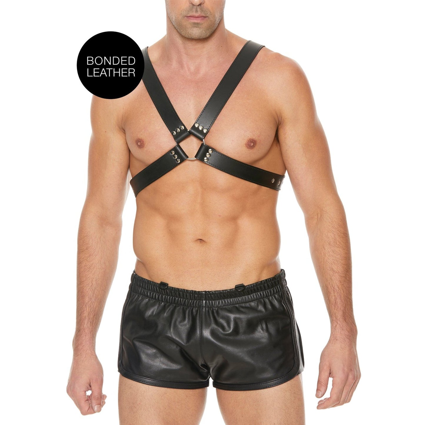 A person wearing the Shots Ouch Mens Large Buckle Harness and leather shorts stands against a plain white background. A circular label, BONDED LEATHER, highlights the stylish use of bonded leather in their daring ensemble.